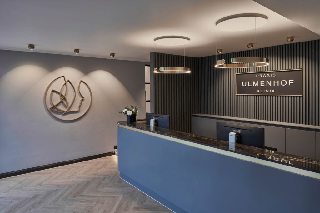 Moderner Empfangsbereich der Zahnarztpraxis Ulmenhof Klinik mit stilvoller Theke und Beleuchtung